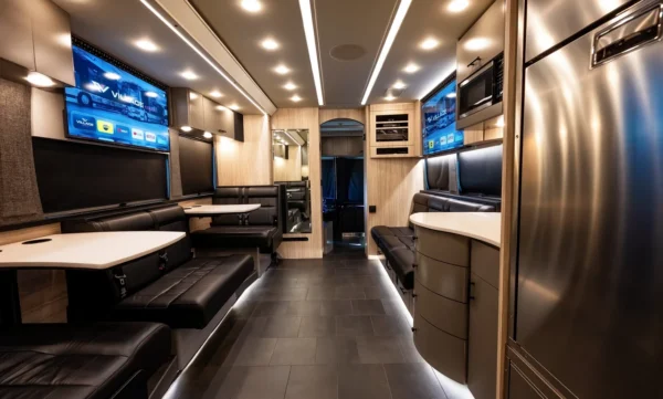 Astro band bus front lounge and galley with leather booths, stainless steel refrigerator, microwave and twin smart TVs