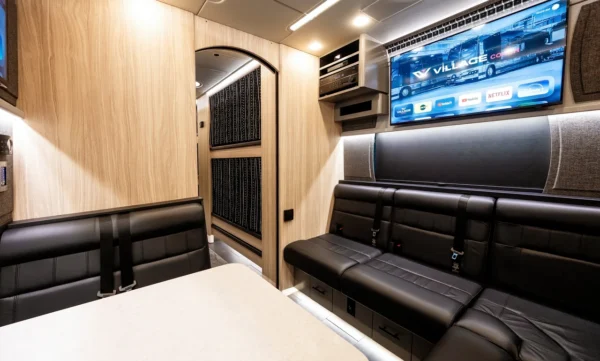 Astro band bus rear lounge with leather bench seating, smart TV and an arched doorway opening to the sleeper bunks