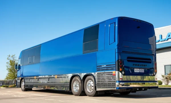 Rear three-quarter view of the Astro entertainer bus, a blue Prevost X3 with polished chrome side panels and tandem rear axles