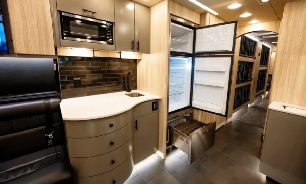 Astro entertainer coach galley with open refrigerator and freezer drawer next to the hallway leading to the sleeper bunks