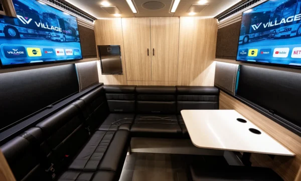 Astro entertainer coach rear lounge with U-shaped black leather sofa, table and two wall-mounted smart TVs