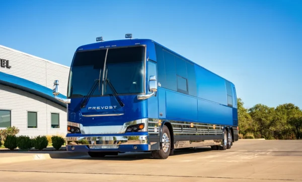 Astro Prevost entertainer coach in metallic blue with chrome trim, front three-quarter view at the Village Coach facility in Wichita