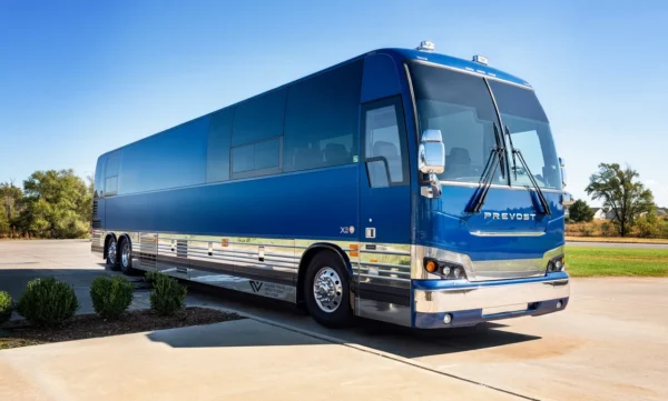 Astro Prevost X3 entertainer bus in metallic blue with chrome trim, front passenger-side three-quarter view