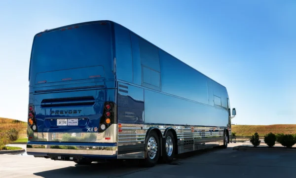 Rear three-quarter view of the Astro tour bus coach, a blue Prevost X3 with polished chrome lower panels