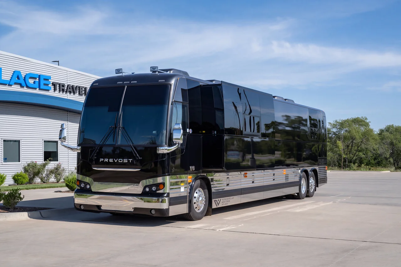 Cash entertainer bus in gloss black with side slide-out extended, parked outside Village Coach in Wichita