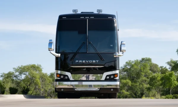 Head-on front view of the Cash tour bus coach, a gloss black Prevost with chrome bumper and mirrors